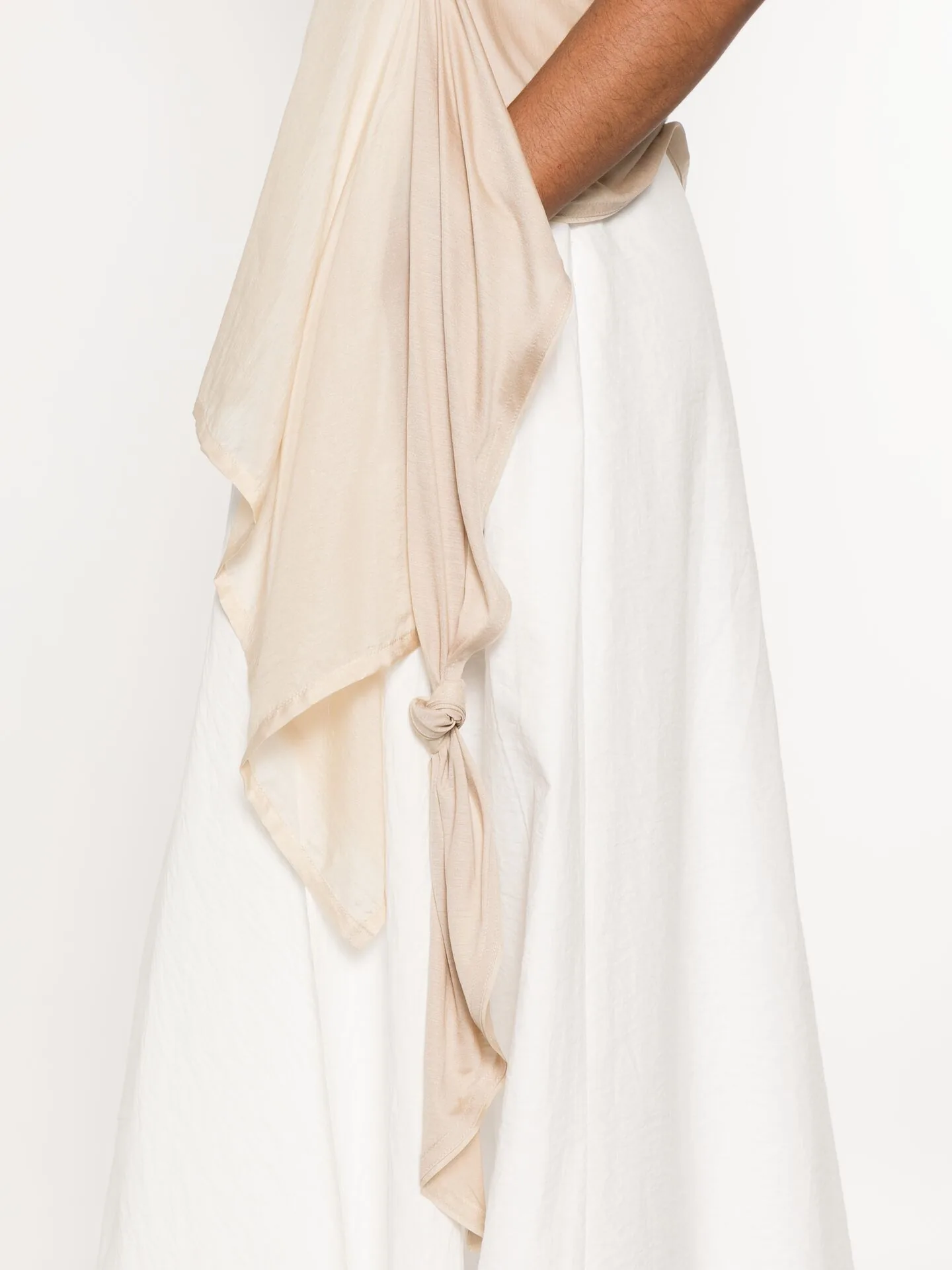 Close crop of cream and white fabric gathered into a soft knot