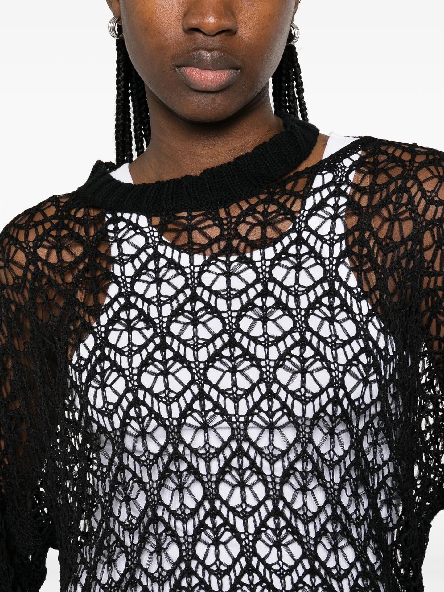 Close crop of a black open-crochet top layered over white