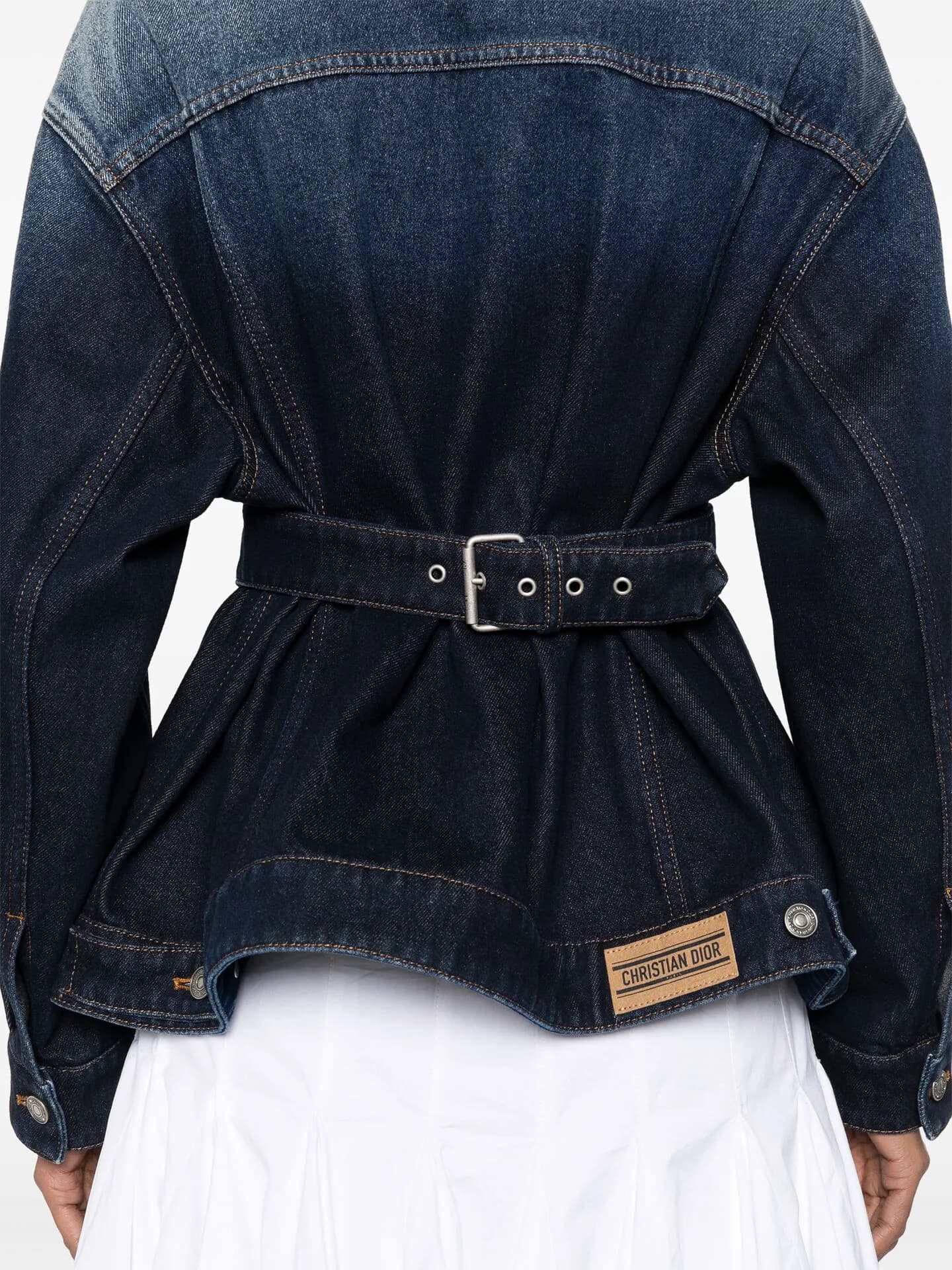 Close crop of a belted dark denim jacket over a white skirt