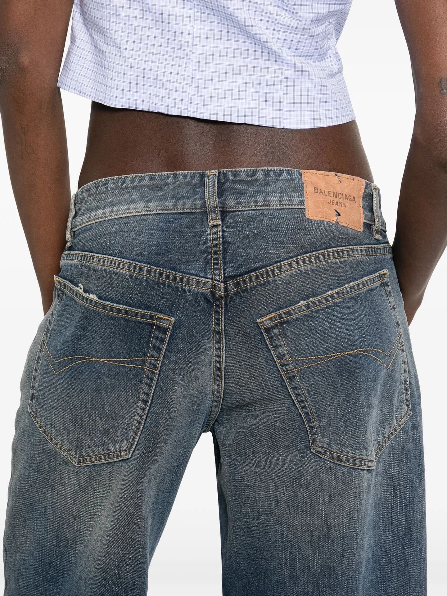 Back view of faded straight-leg jeans worn with a white checked top