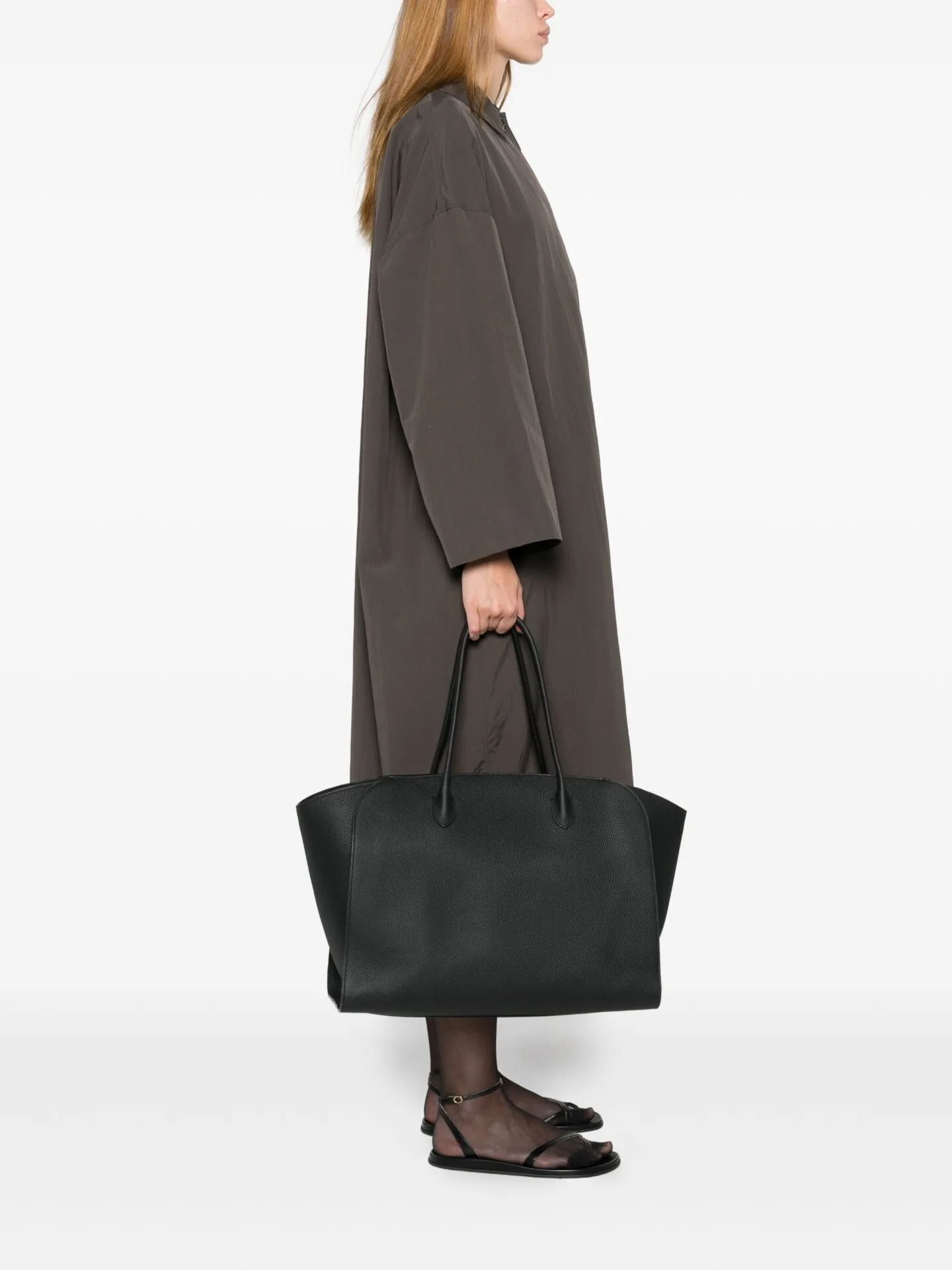 Model in a long grey-brown coat carrying a large black leather tote