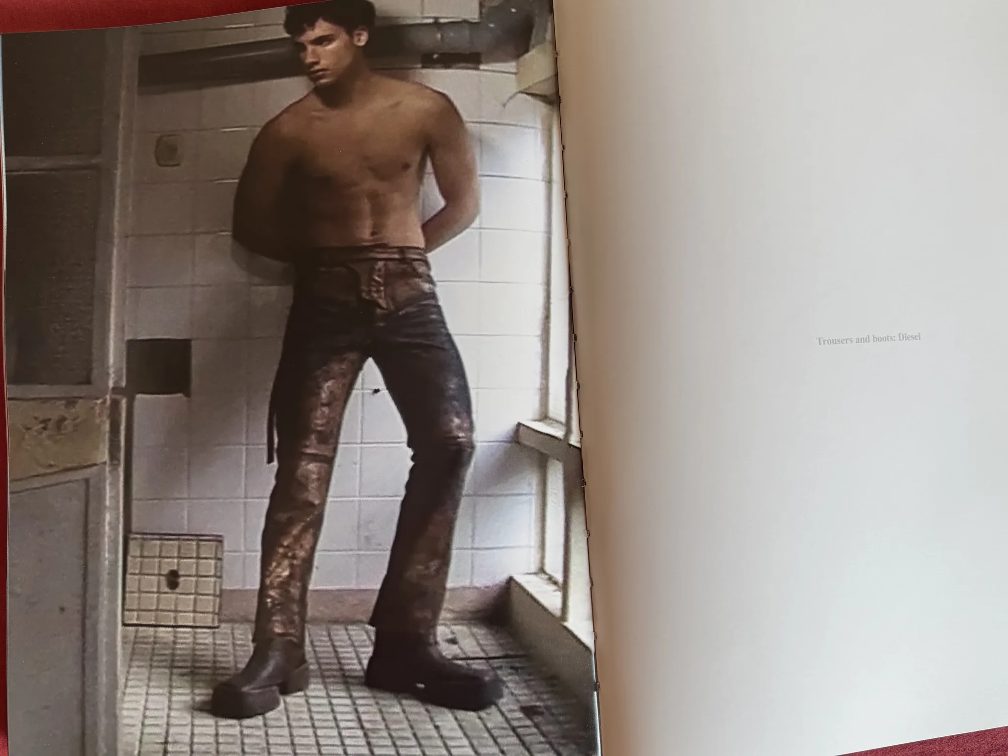 Magazine spread: model standing in a white-tiled bathroom in distressed printed trousers and heavy boots