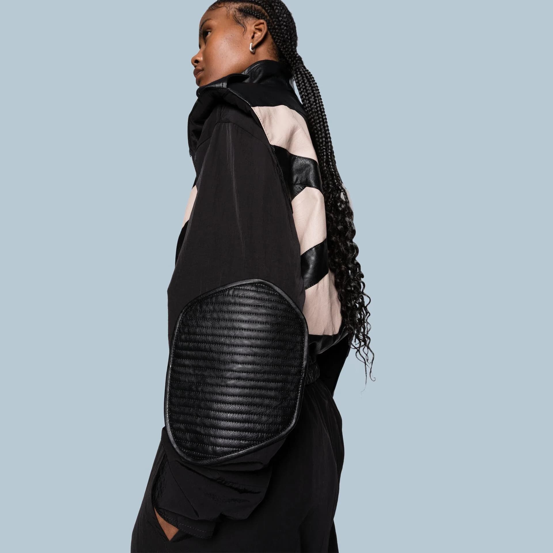 Side view of a black and cream padded jacket with a quilted shoulder panel