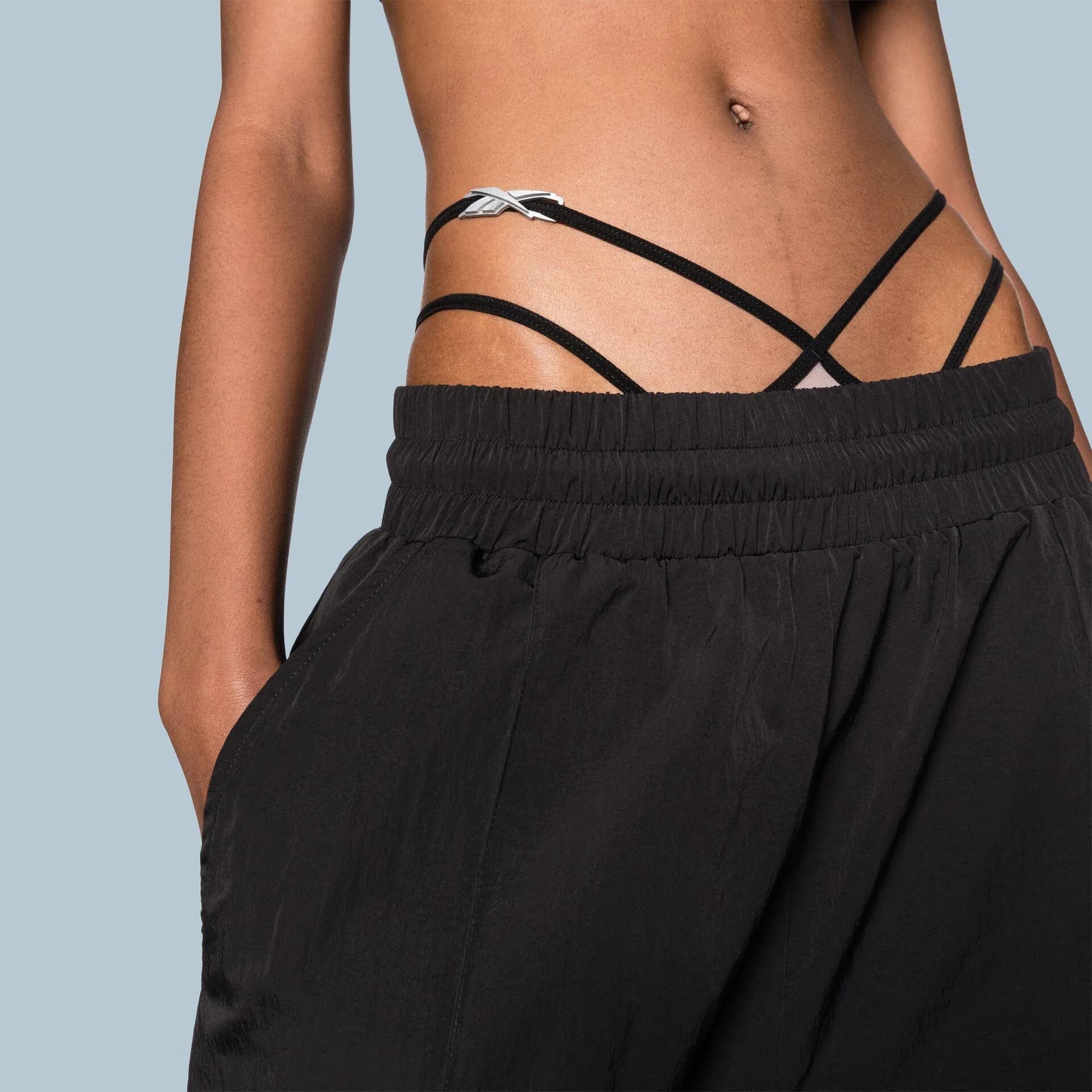 Close crop of black drawstring trousers with a strappy bodysuit at the waist