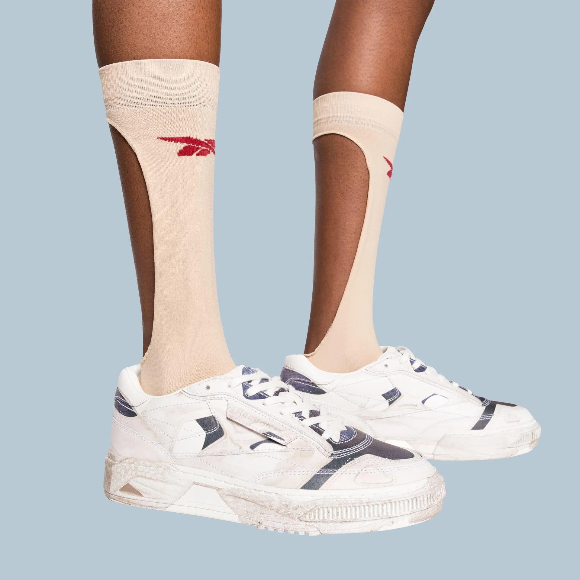Sheer cream socks with red Reebok logos above white and navy trainers