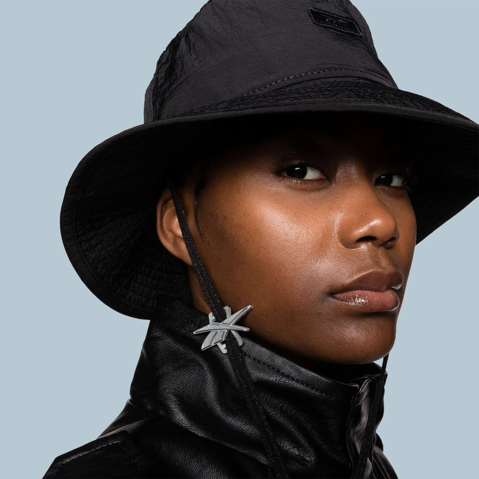 Close portrait of a model in a black nylon bucket hat and leather jacket