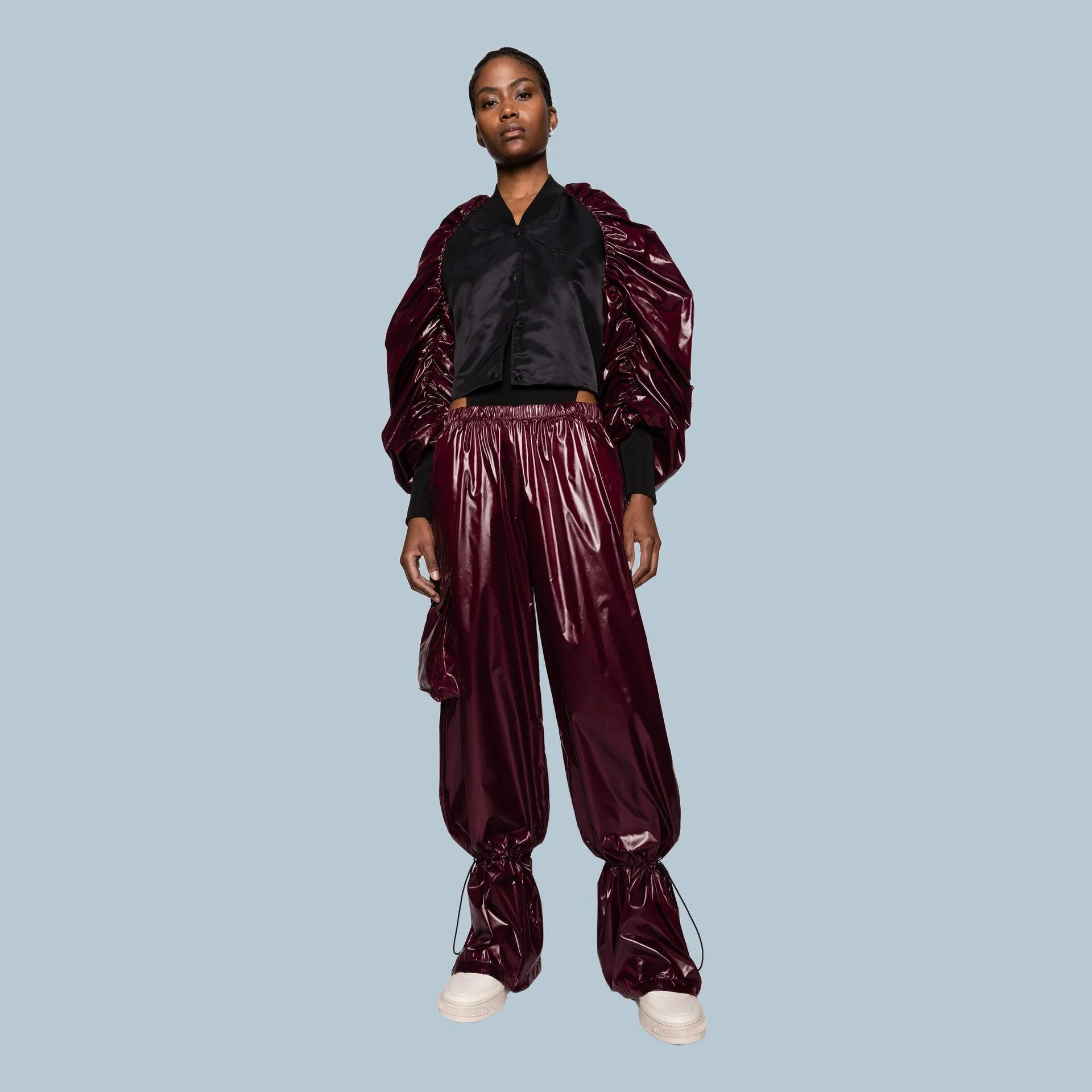 Model in a black shirt and burgundy high-shine track trousers