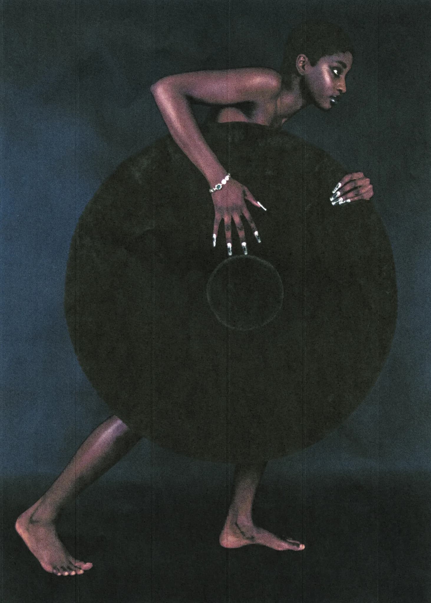 Model standing behind a large black disc, long silver nails spread across its face