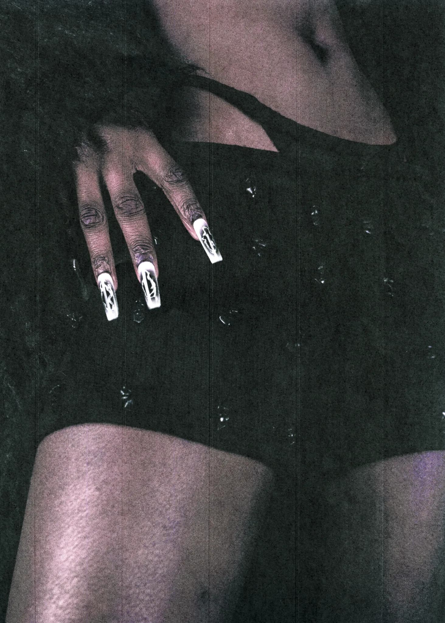 Close crop of long white-tipped nails resting against a black beaded bodysuit