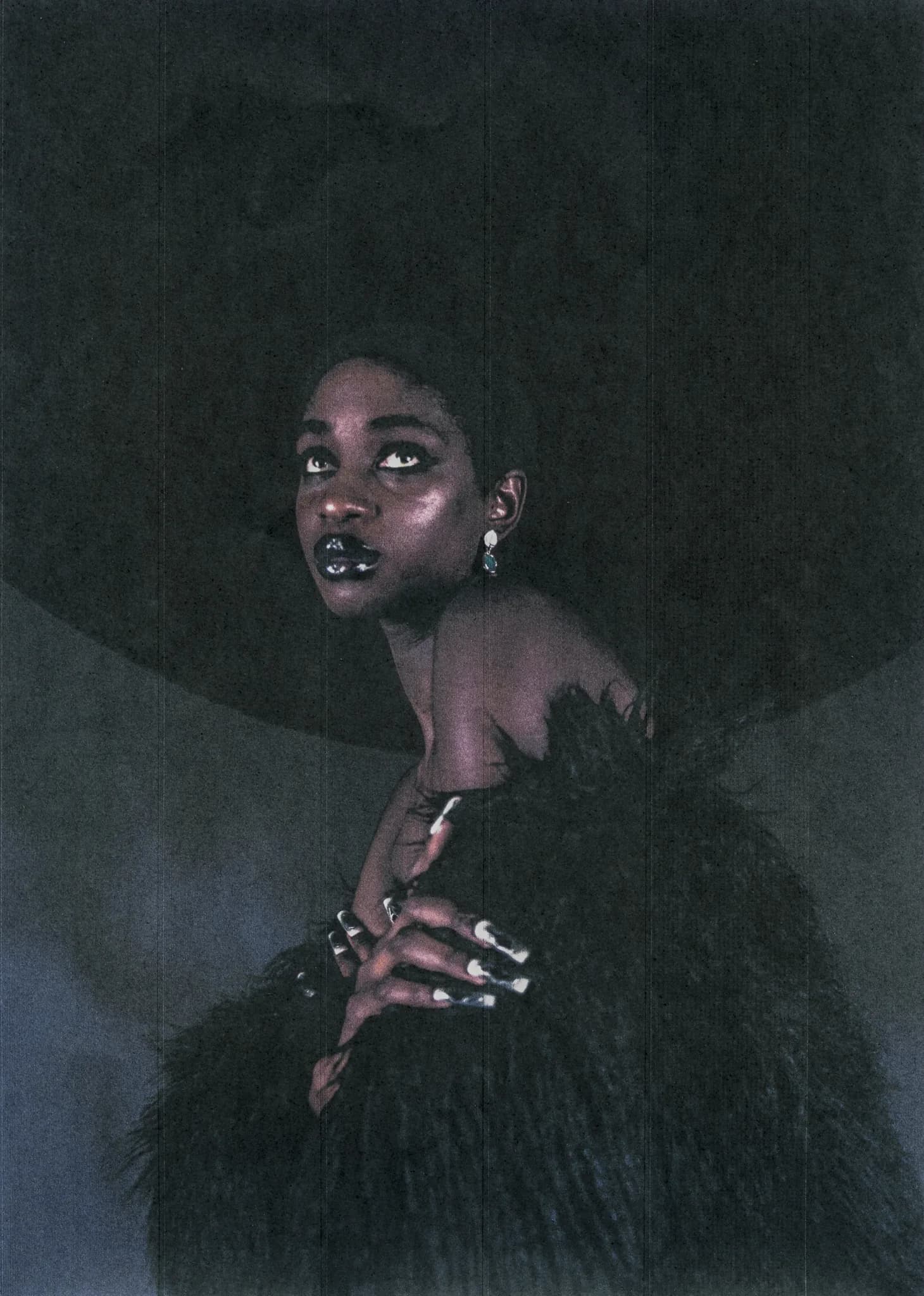 Model in black fur with hooped earrings, hands raised beneath the chin