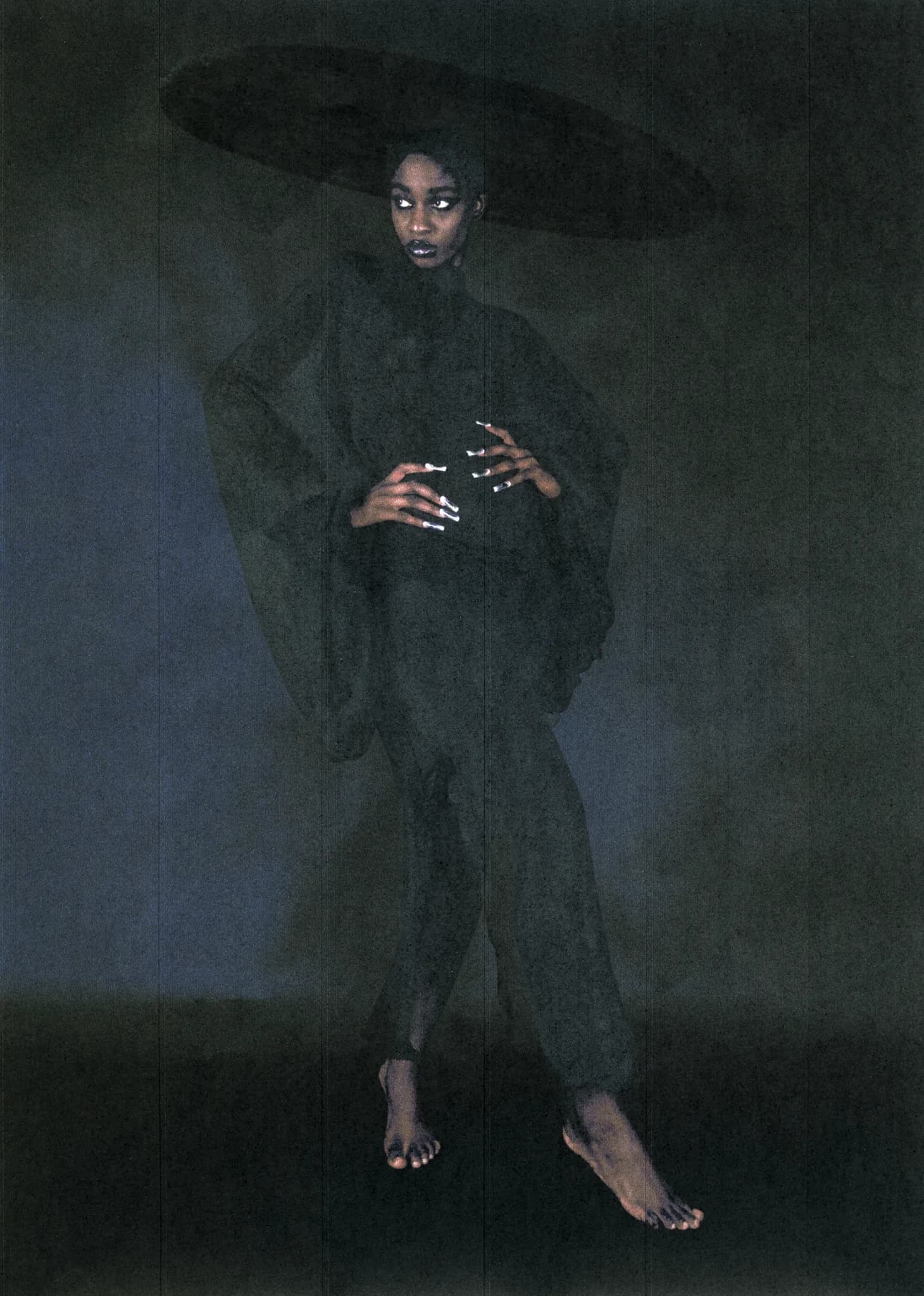 Full-length portrait of a model barefoot in a black suit and wide-brimmed hat